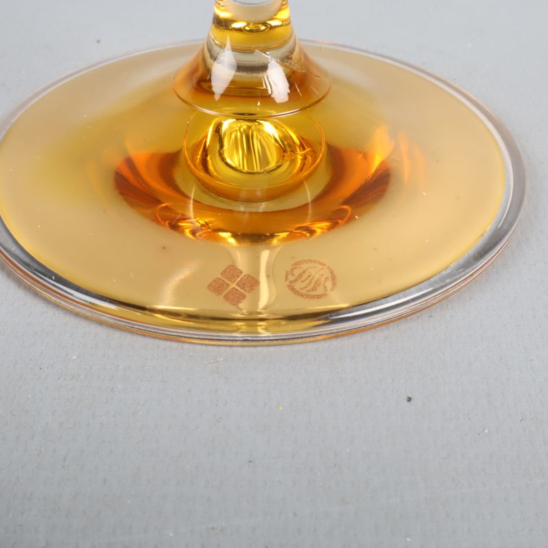 Närbild av guldfärgad glasfot med fyrklövern logo
