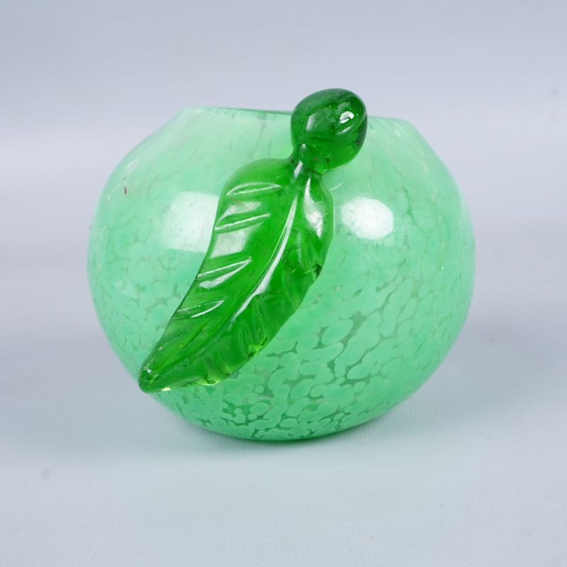 Grön glasljusstake med lövdetalj i närbild