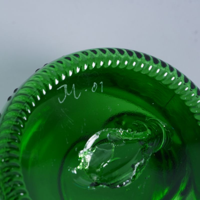 Närbild på vasens signerade botten i grönt glas