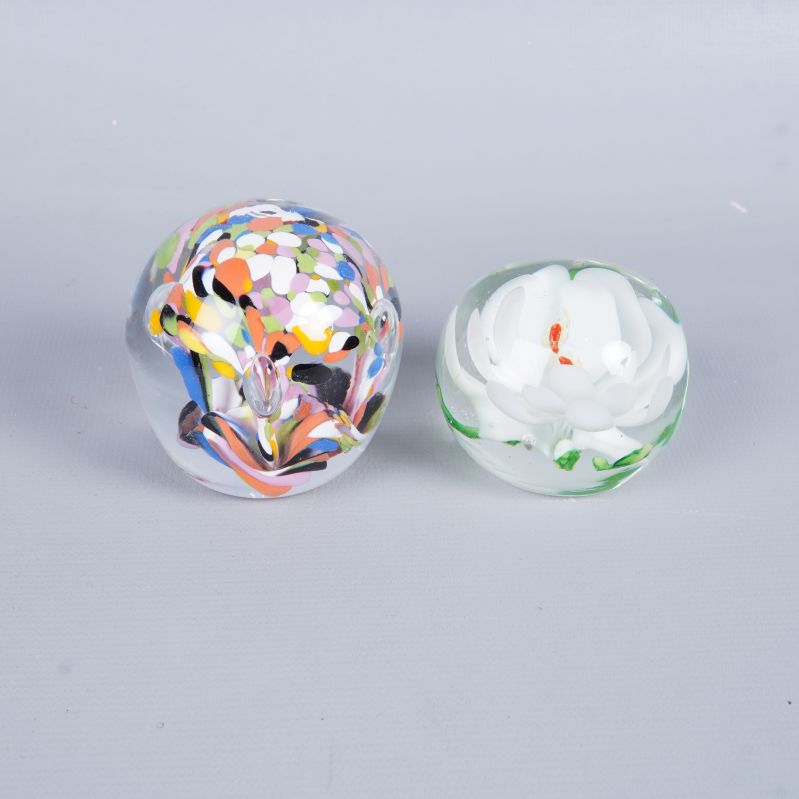 Två brevpressar, en färgglad och en med vit blomma