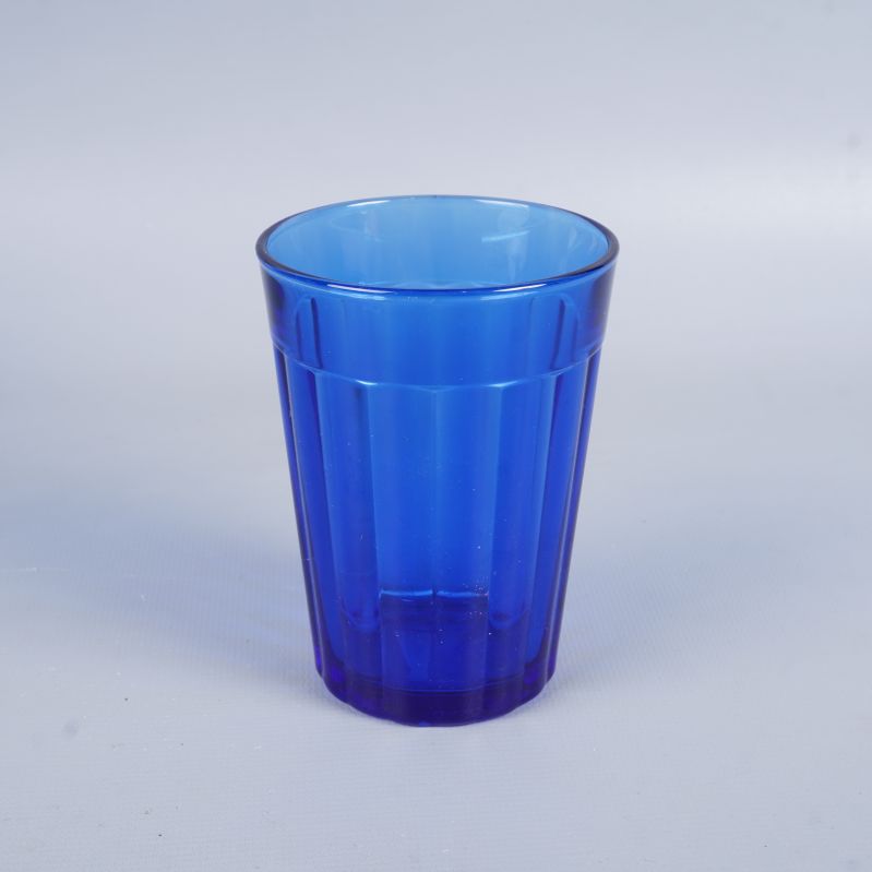 Ett blått dricksglas i närbild mot vit bakgrund