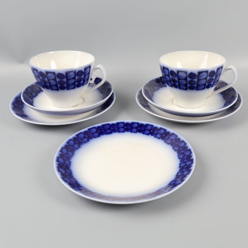 Två tekoppar med blå dekor och fat samt assietter