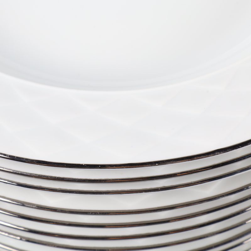 Närbild på silverkant och reliefmönster på tallrikarna