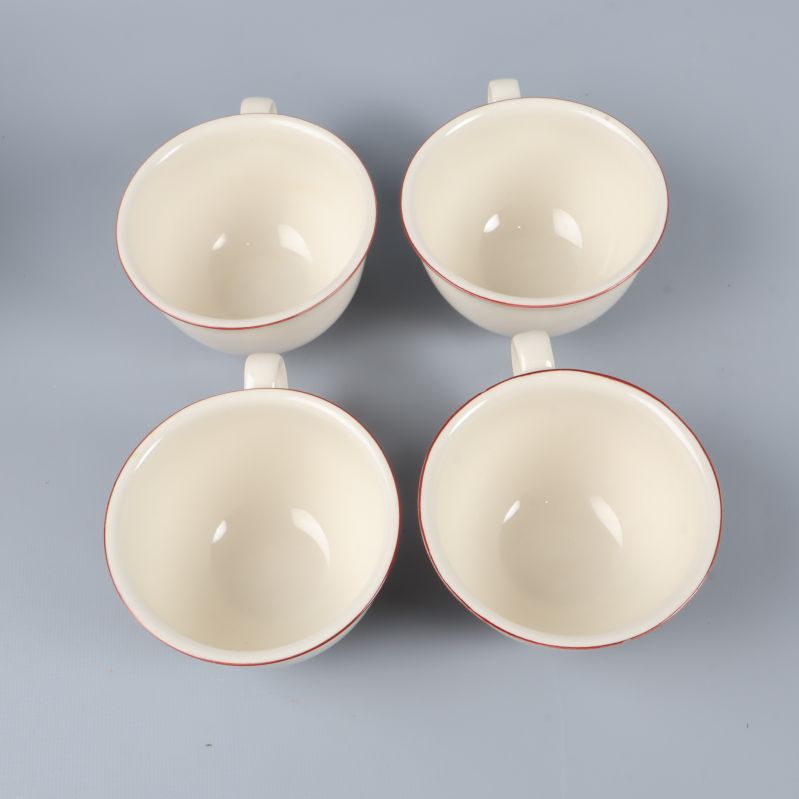 Fyra gräddvita koppar sedda ovanifrån med röd kant