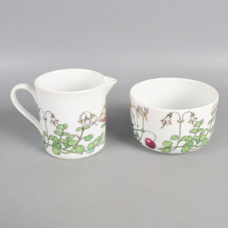 Baksidan av kanna och skål visar grön bladdekor och rosa blommor