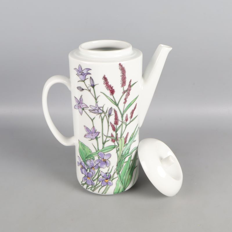 Öppen kanna med blomdekor och avtaget lock bredvid