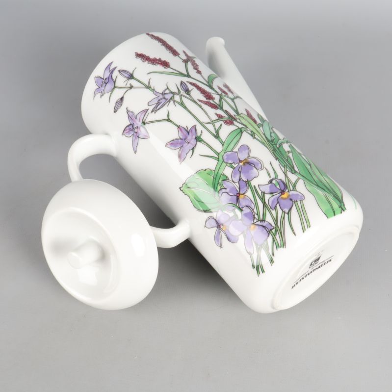 Kanna liggande med lock på sidan och blommönster synligt