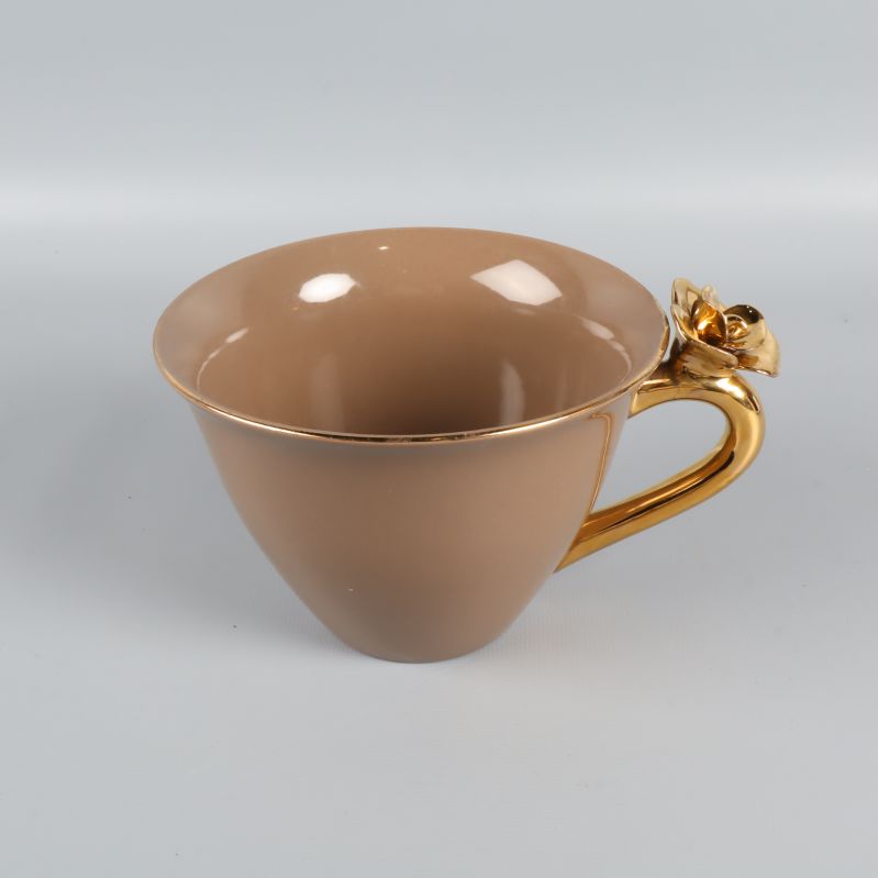 Beige tekopp med guldfärgat handtag och blomma