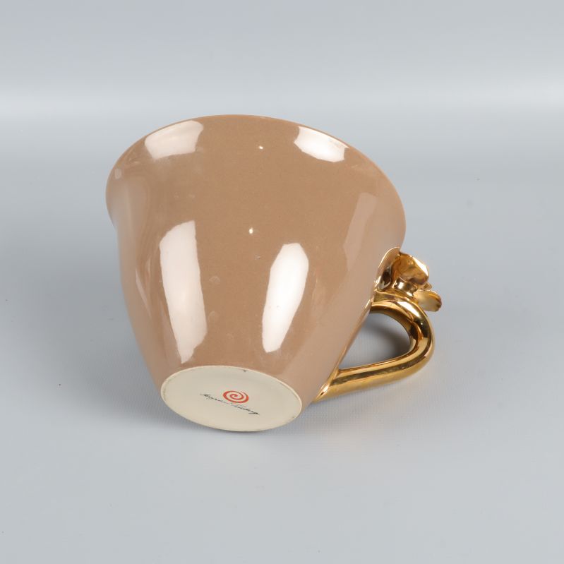 Beige tekopp med bottenstämpel och guldfärgat handtag