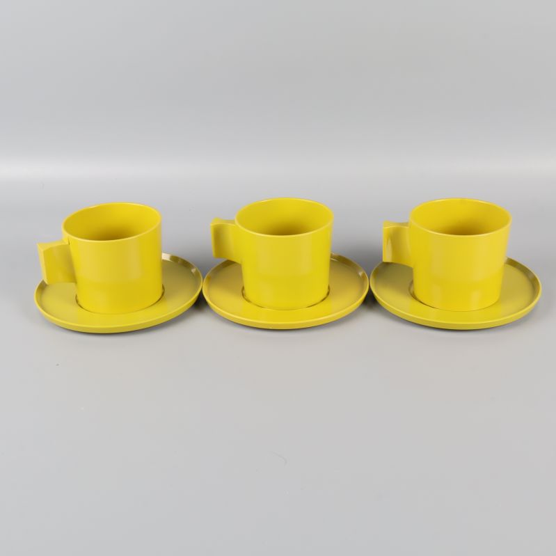 Tre gula/gröna koppar med fat i rad