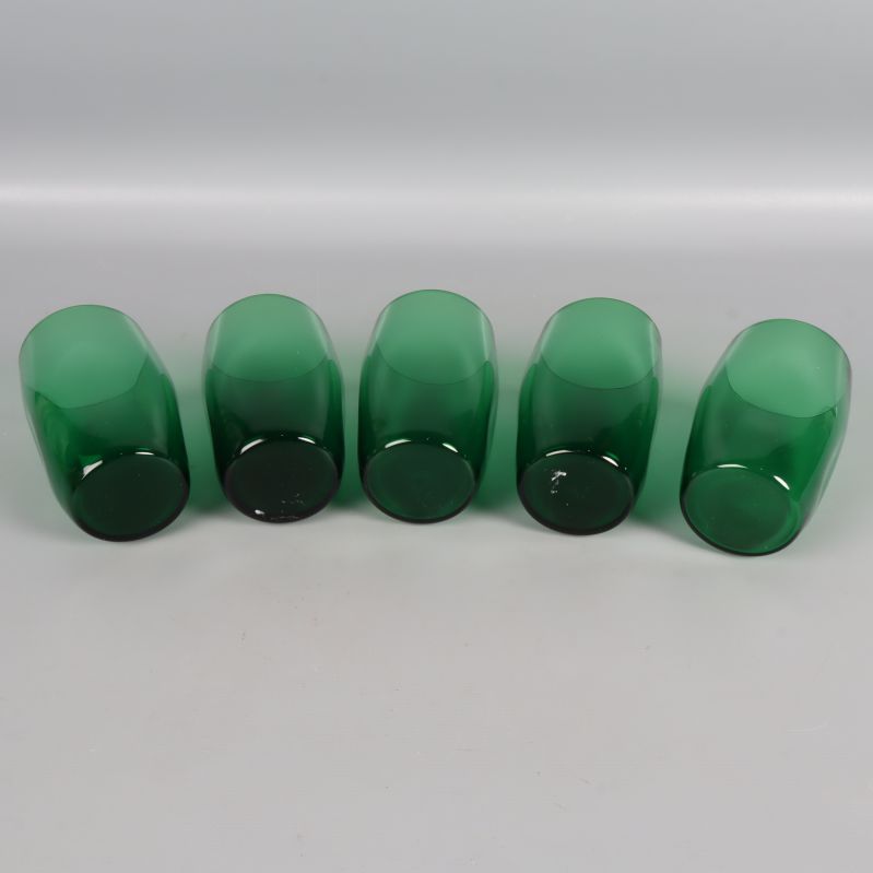 Botten på fem gröna selterglas liggande nedåt