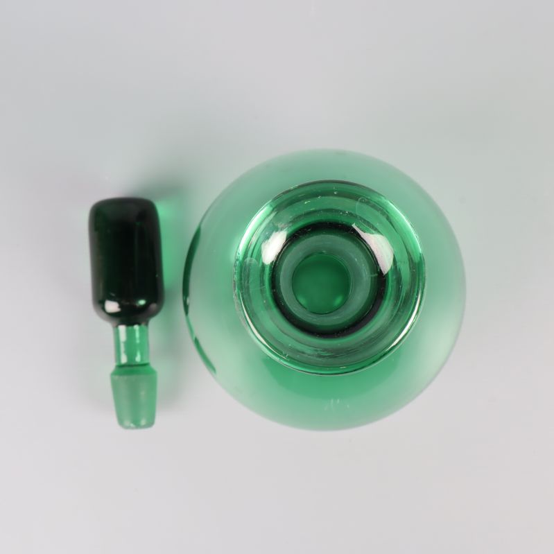 Vy ovanifrån på öppnad karaff och grön knopp