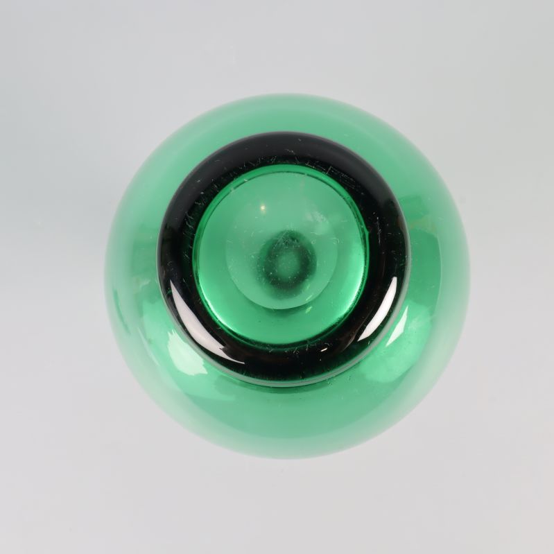 Botten på grön glasflaska fotad rakt uppifrån