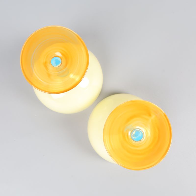 Botten av två cocktailglas med orange bas och blå detalj