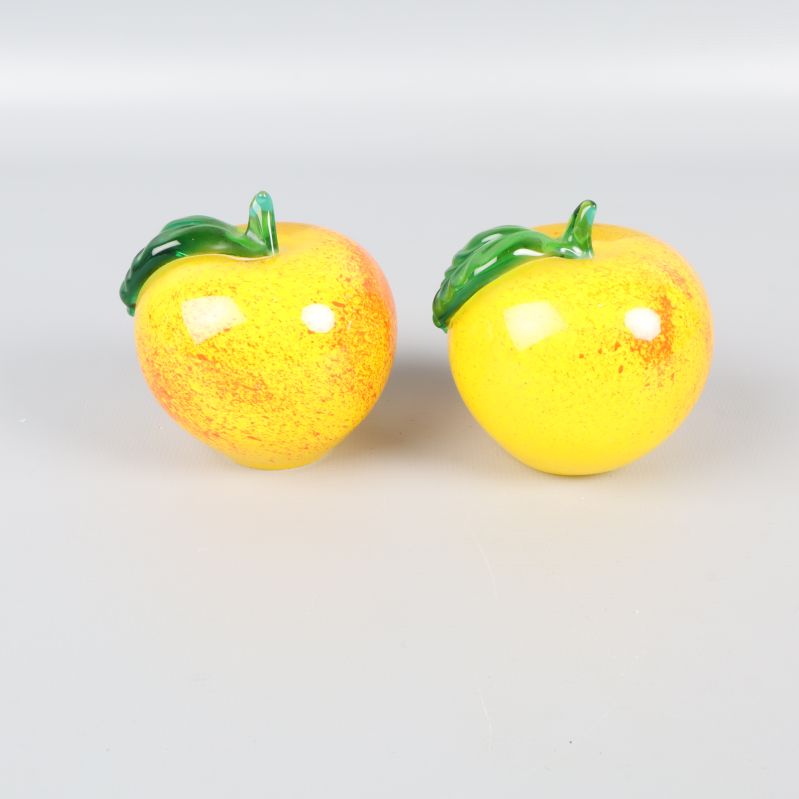 Två gula glasäpplen med gröna blad