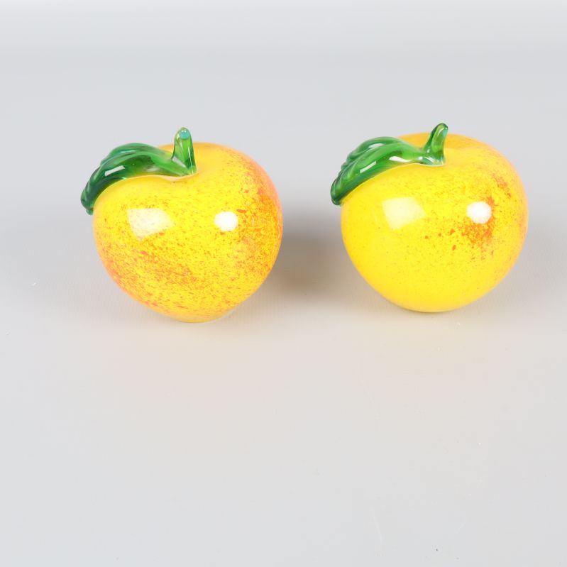 Två glasäpplen med blanka ytor och gröna blad