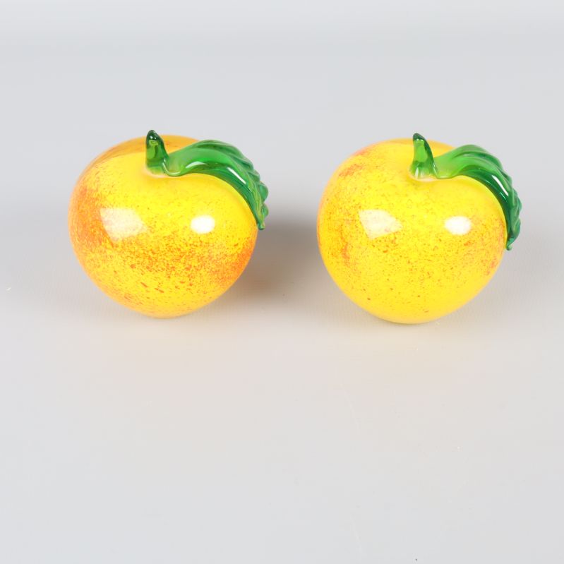 Dekorativa glasäpplen med gul yta och grönt blad