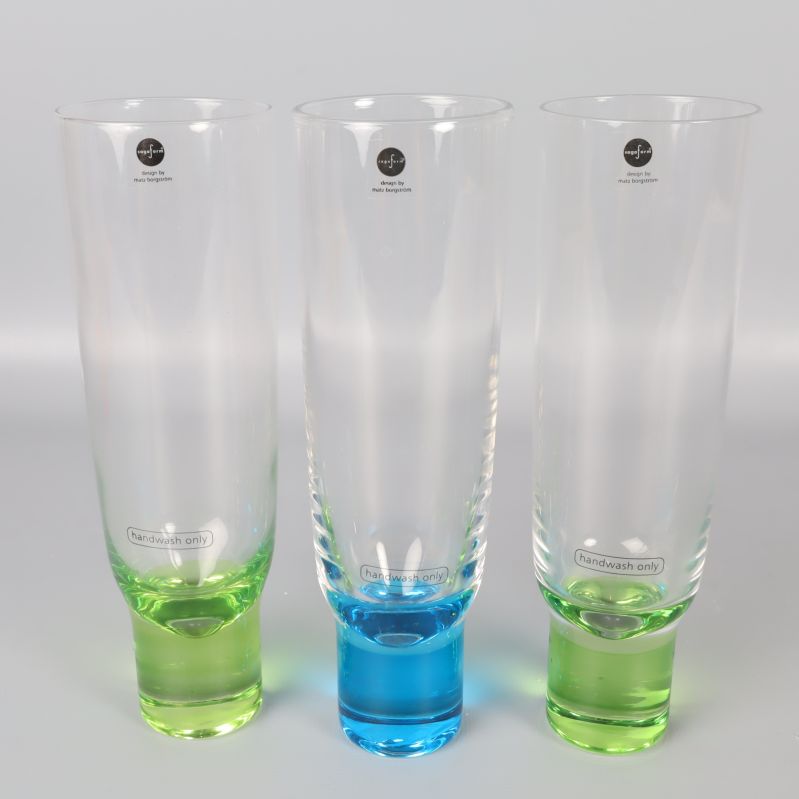 Tre champagneglas med grön och blå fot sida vid sida