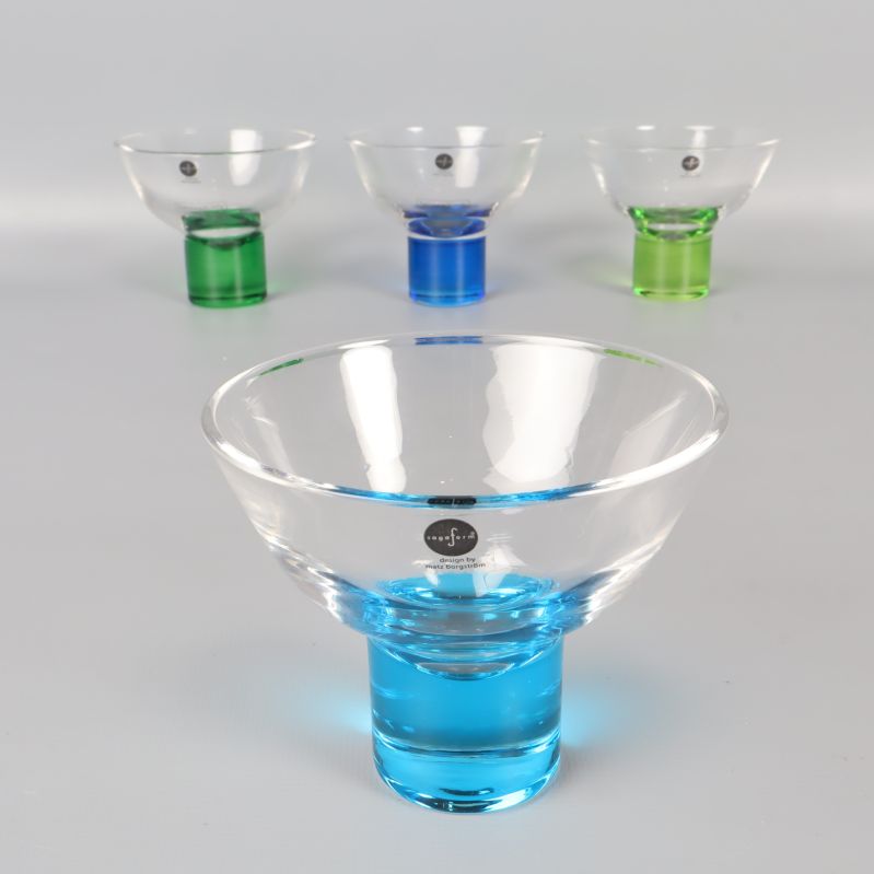 Glas med blå fot framifrån, övriga skålar i bakgrunden