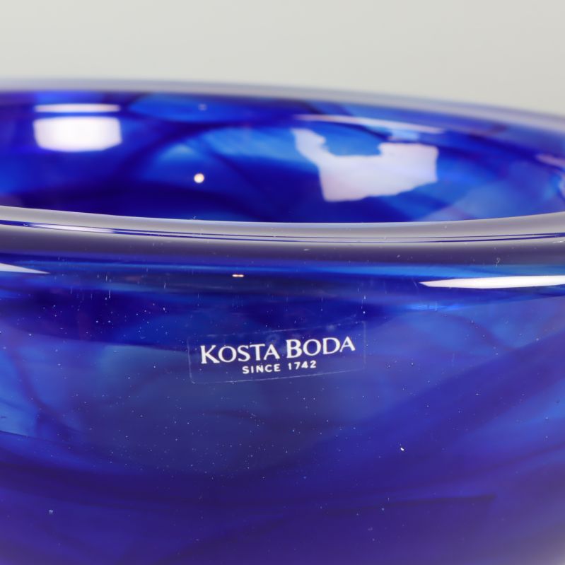 Närbild på Kosta Boda logotyp på blå glasskål