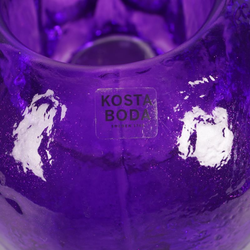 Närbild på Kosta Boda-logotyp på lila dödskalle ljushållare