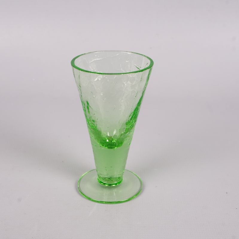 Närbild på ett grönt likörglas med fot