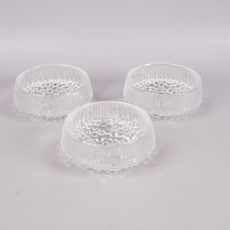 Tre runda glasskålar med bubblig textur stående på vit yta