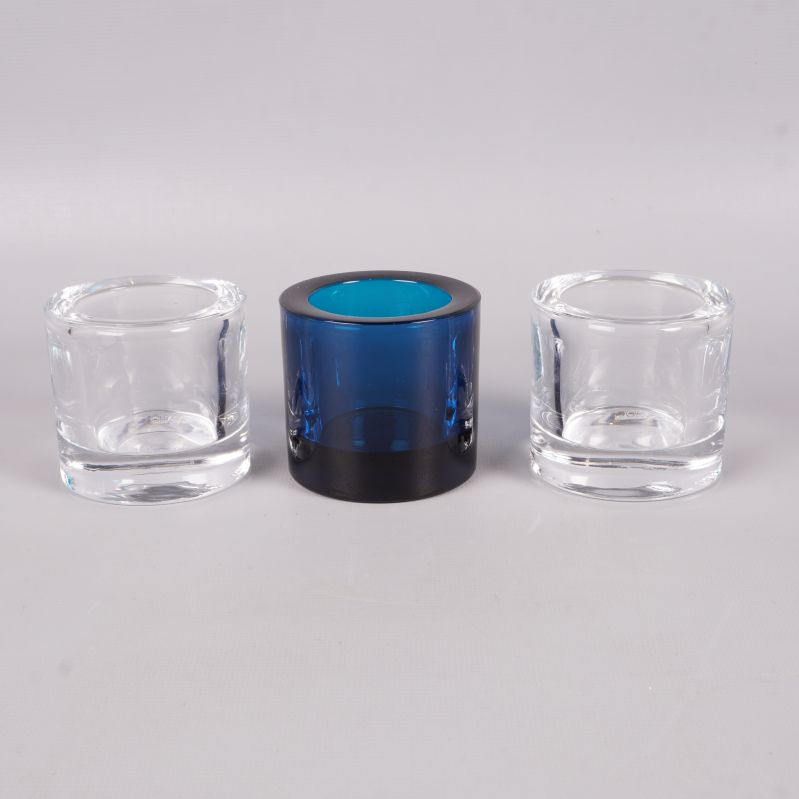 Framifrån av tre glasljushållare, en färgad