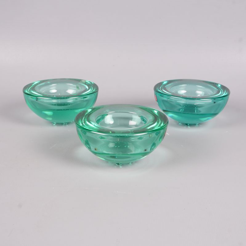 Tre gröna glaskandelabrar fotade snett bakifrån