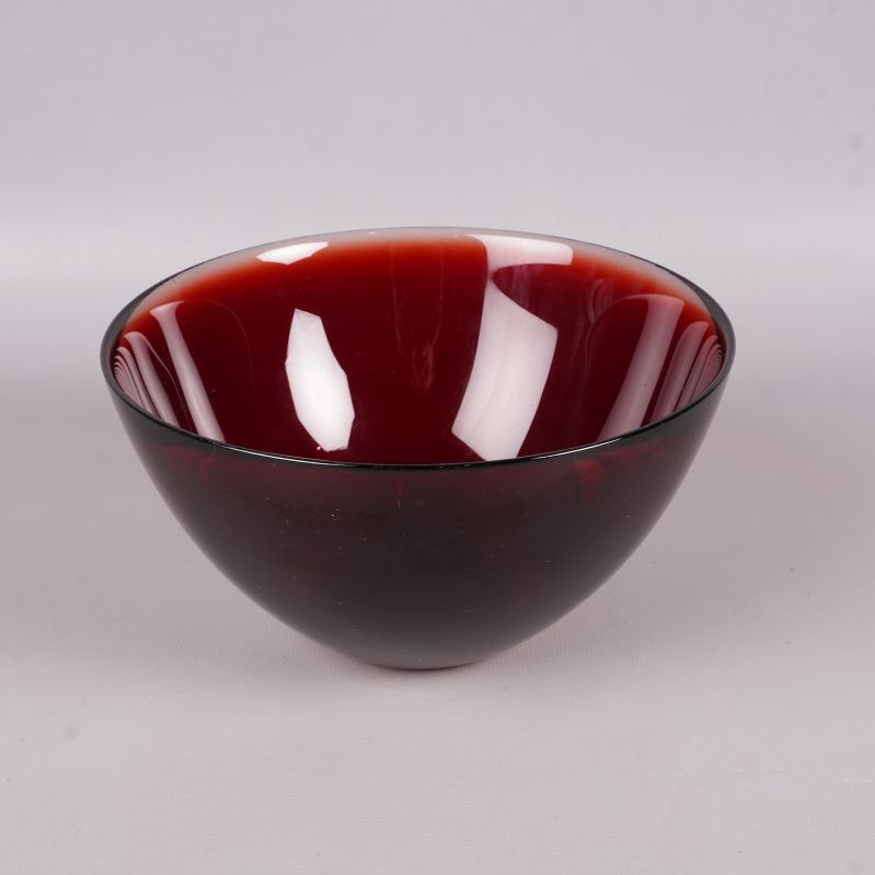 Röd glasskål med rund form sedd snett framifrån