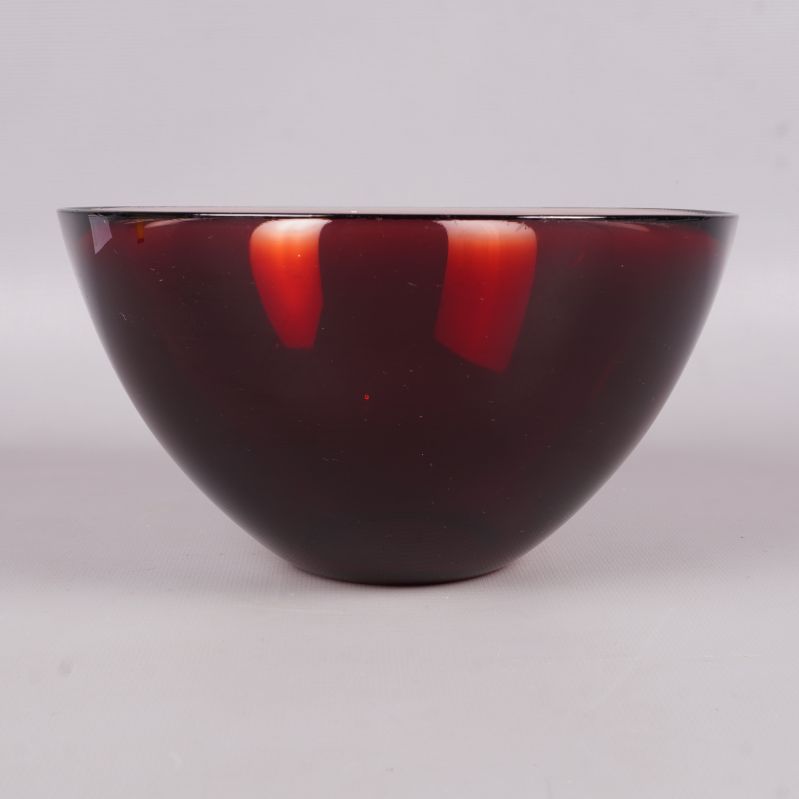 Röd glasskål sedd från sidan mot vit bakgrund