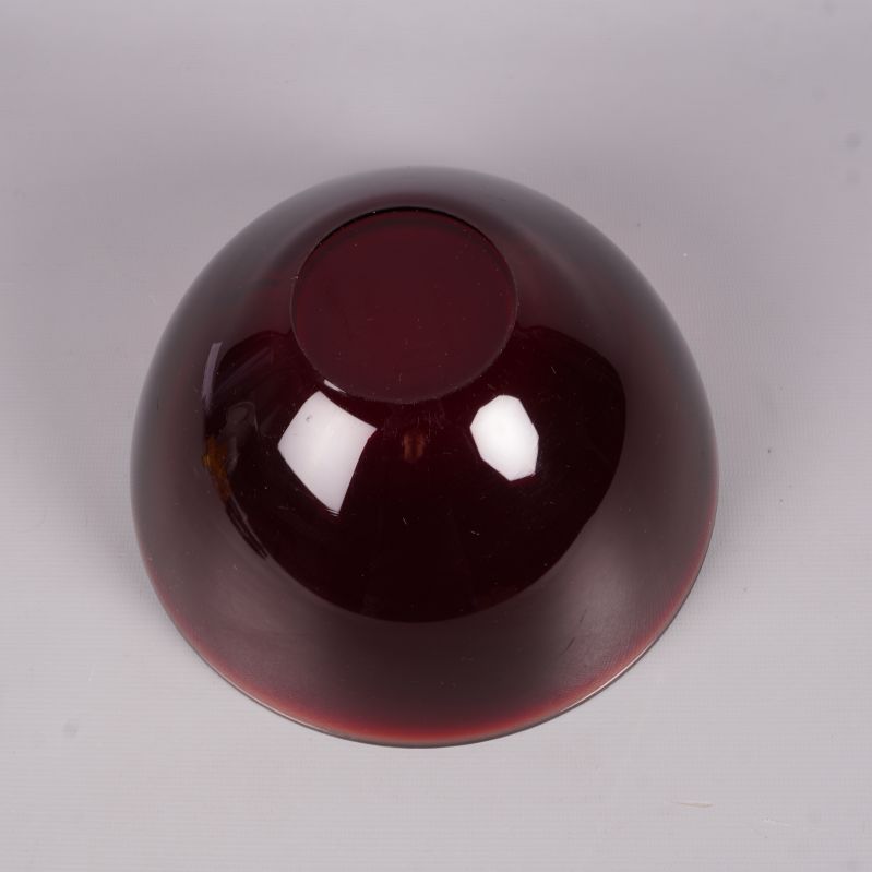 Undersida på röd glasskål med markerad fot