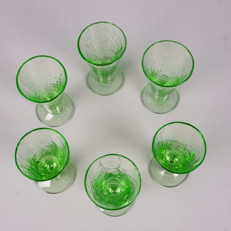 Sex gröna likörglas sedda ovanifrån i en cirkel