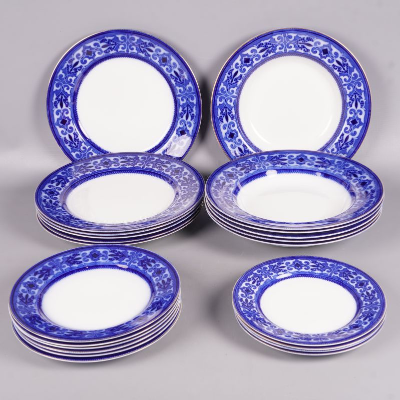 Flera tallrikar med blå mönstrad kant staplade mot grå bakgrund