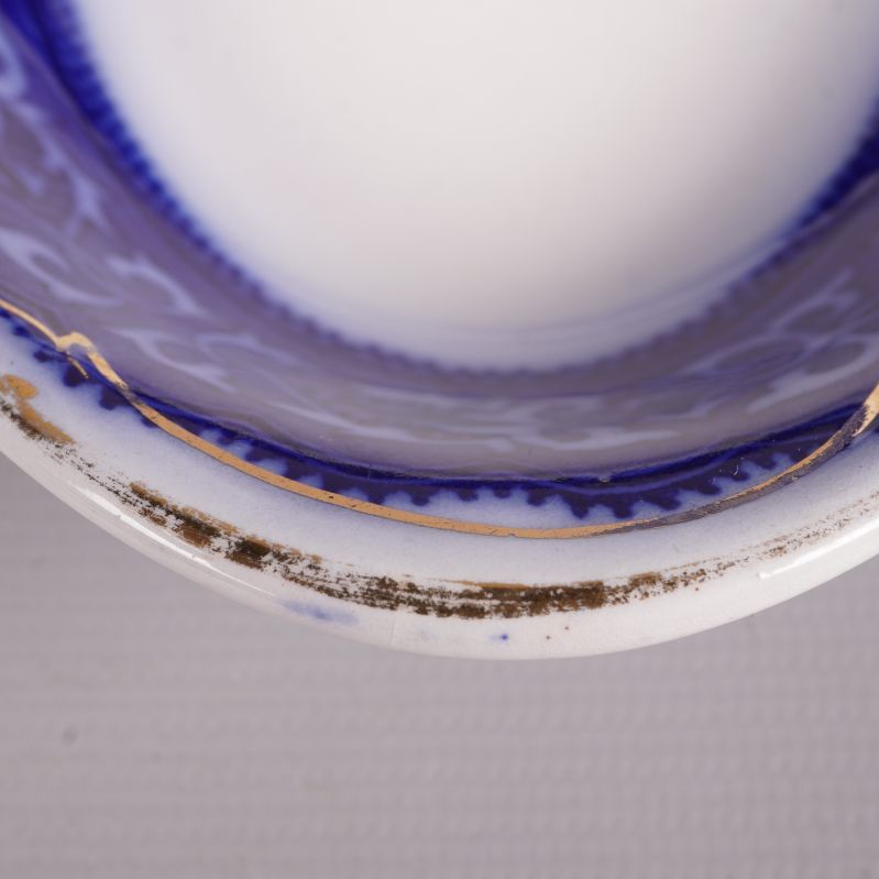 Närbild på slitage och gulddetaljer på skålens kant