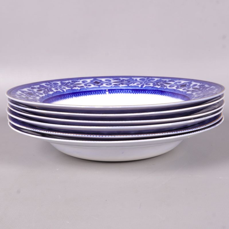 Sex djupa tallrikar med blå kant staplade på varandra