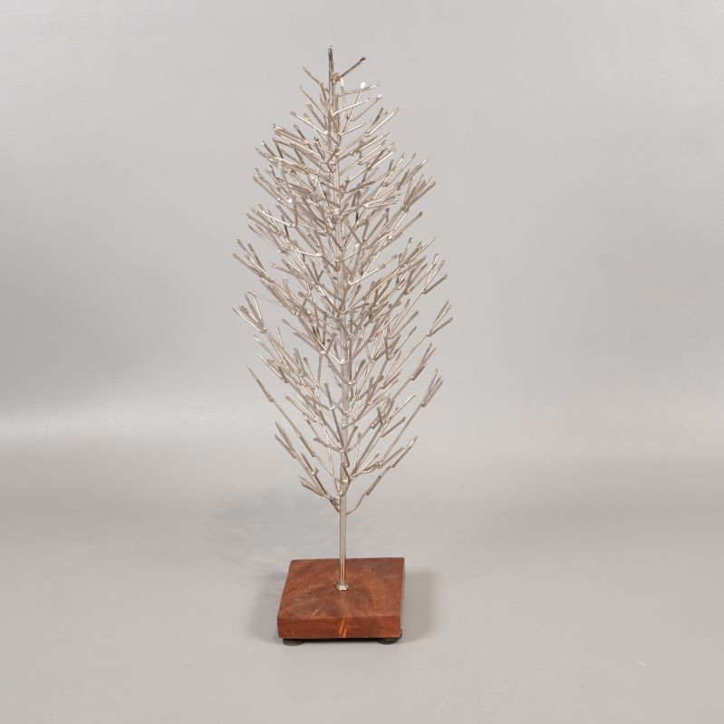 Julgran i metall på brun träbas mot ljus bakgrund