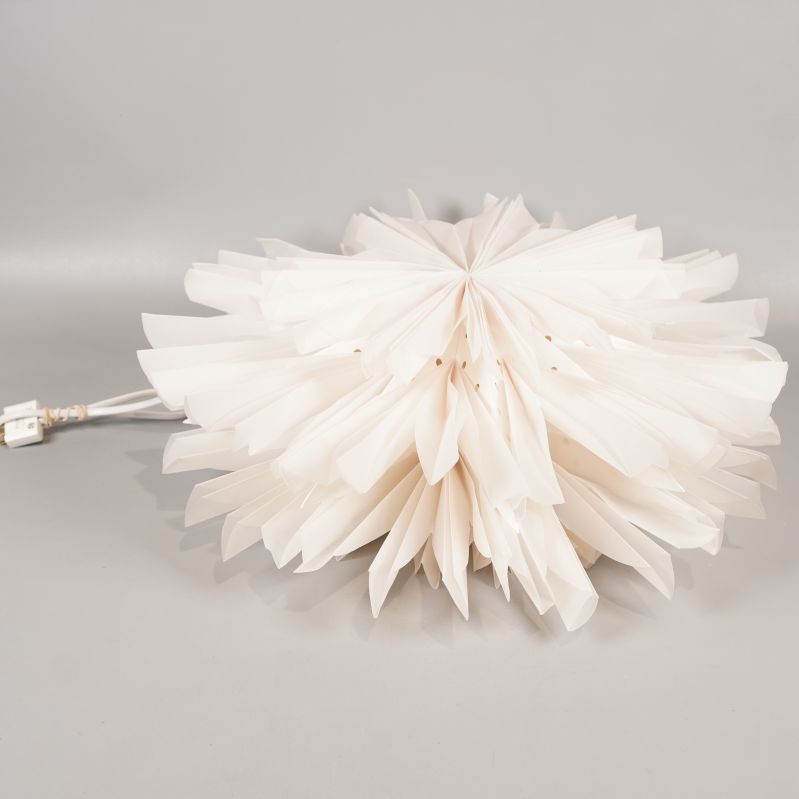 Pappersstjärna fotograferad från sidan liggande på grå yta