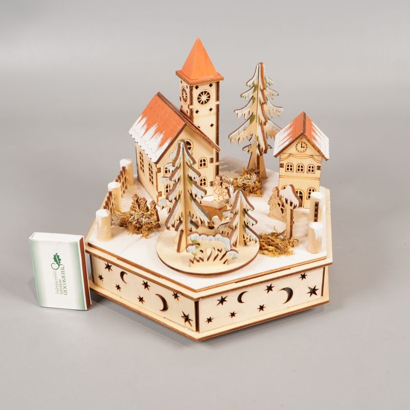 Detaljerad julby i trä bredvid tändsticksask för storleksreferens