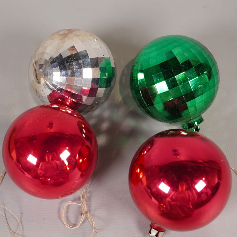 Närbild på silverfärgad, grön och två röda julgranskulor