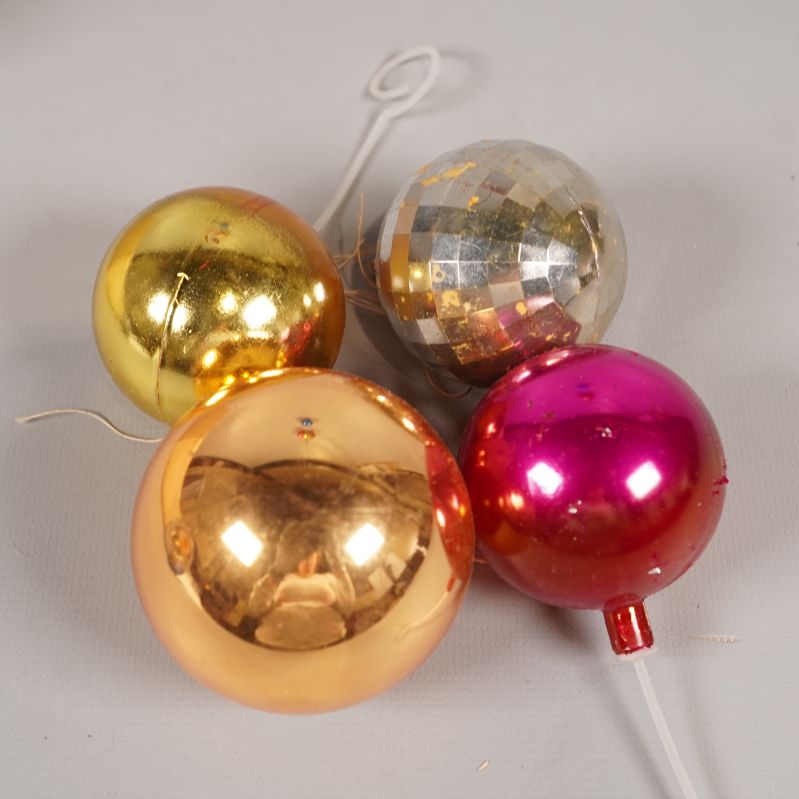 Närbild på silverfärgad, rosa och två guldfärgade julgranskulor