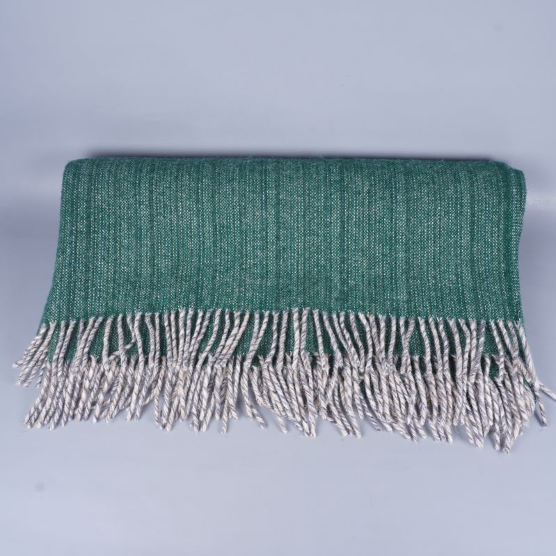 Grön lammulls filt vikt med vita fransar