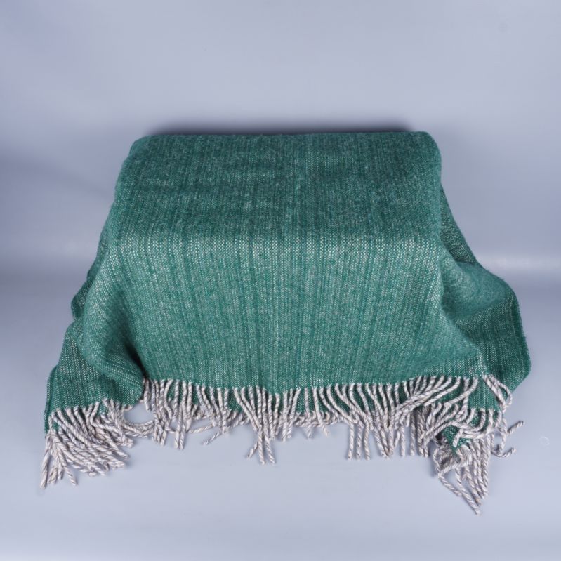 Utbredd grön filt med fransar över en stol