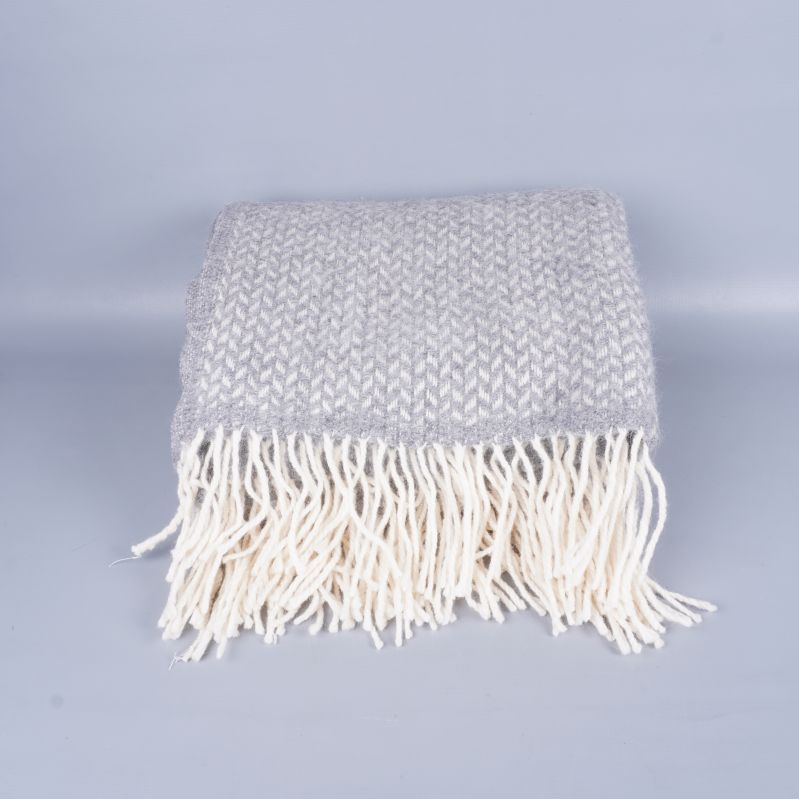 Pläd i grått och vitt med tydligt fiskbensmönster och fransar