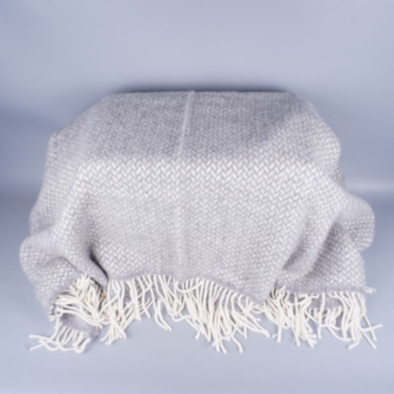 Stor pläd i grått och vitt med fiskbensmönster över yta