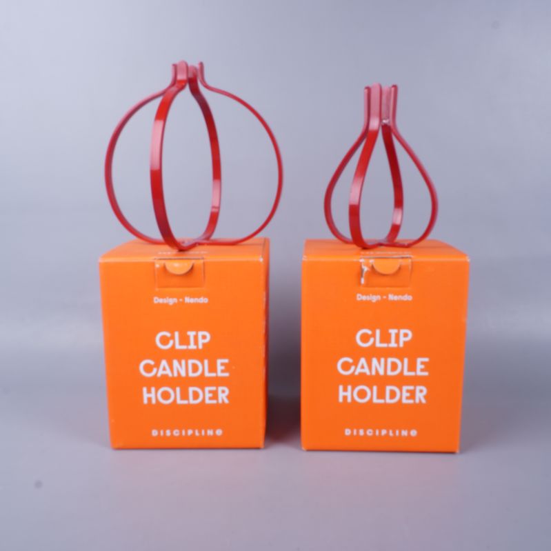 Två röda ljushållare på orange förpackningar