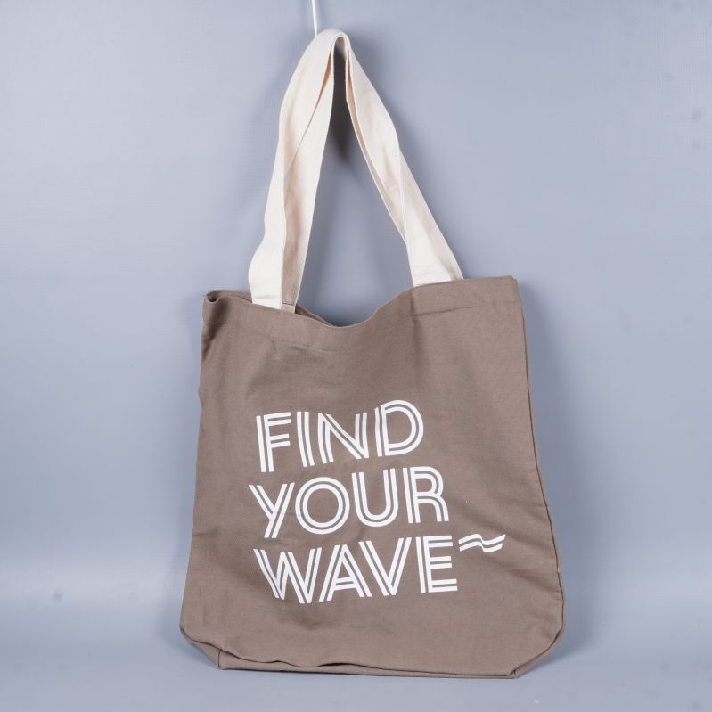 Beige tygkasse med vitt tryck och ljusa handtag hängande