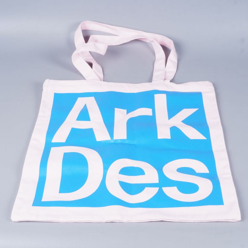 Tygkasse med blå och rosa detaljer, liggande på grå yta