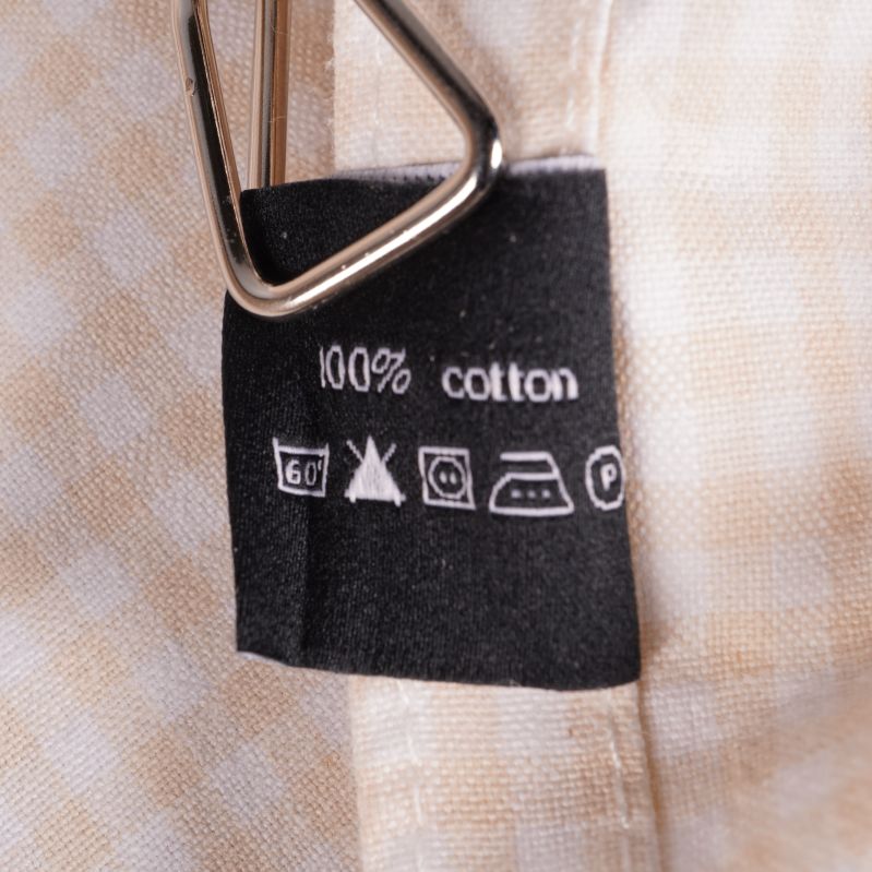 Svart skötseletikett på tygservett visar 100% cotton