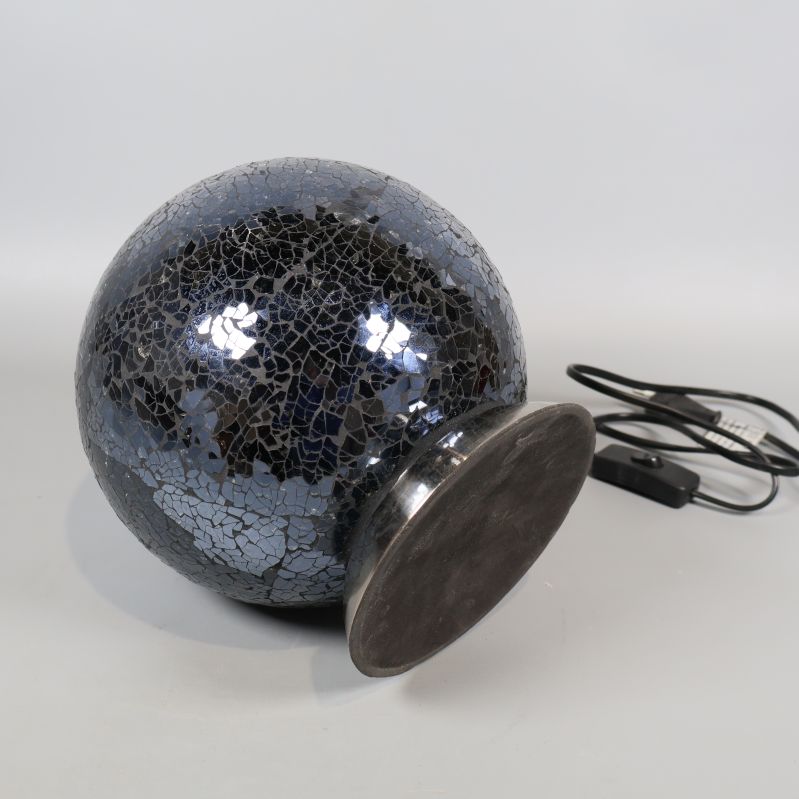 Mosaiklampa ligger ned, visar undersidan på metallfoten